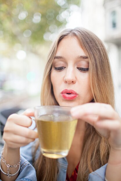 屋外の紅茶で吹くかわいい女性