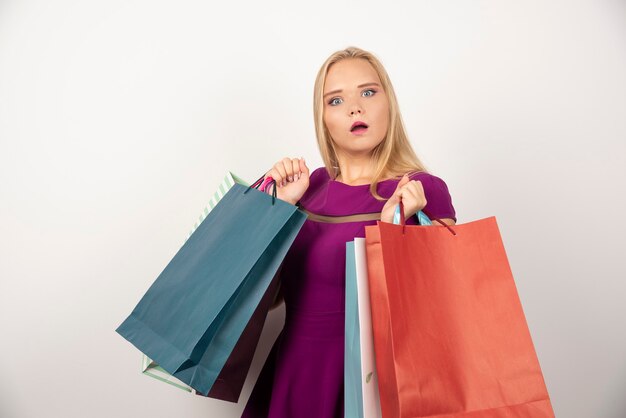 Pretty woman carrying colorful shopping bags with puzzled expression.