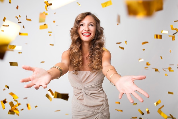 Free photo pretty woman celebrating new year in golden confetti