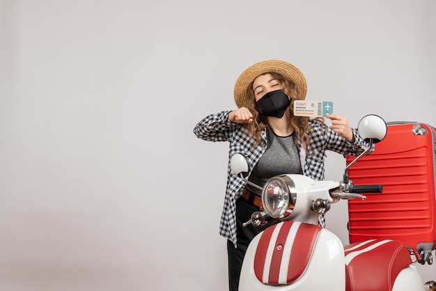 pretty woman closing eyes holding ticket standing near moped red suitcase