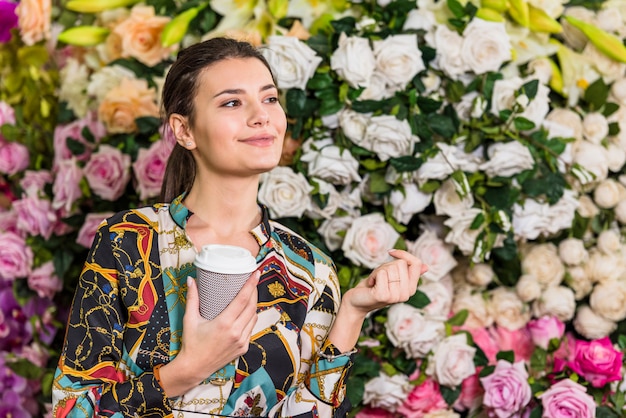 Pretty woman drinking coffee in green house