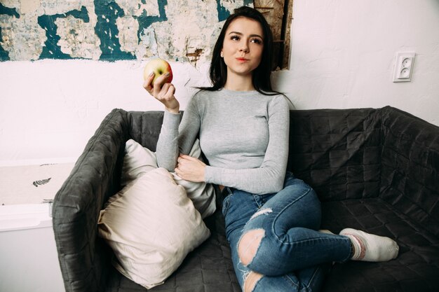 Pretty woman eats apple sitting on black chair