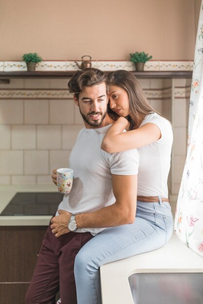 Pretty woman embracing boyfriend with mug