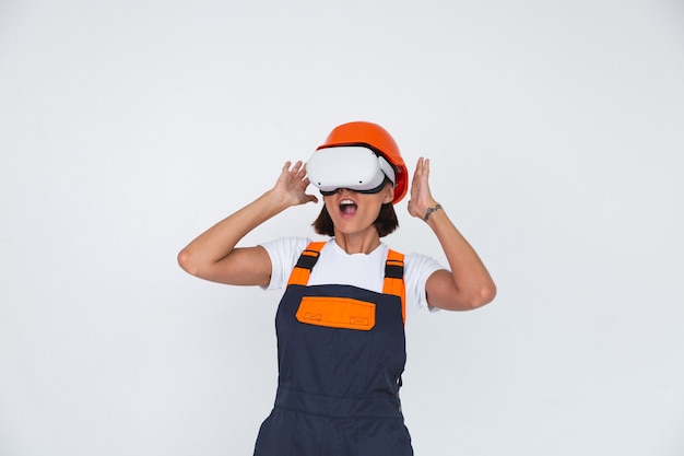 Pretty woman engineer in building protective helmet on white  in virtual reality glasses