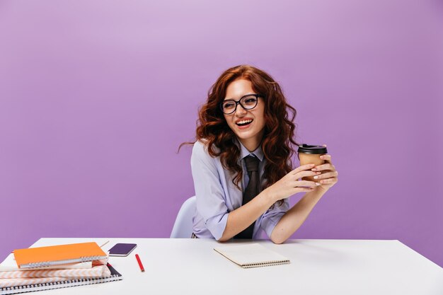 Pretty woman in eyeglasses holds coffee cup