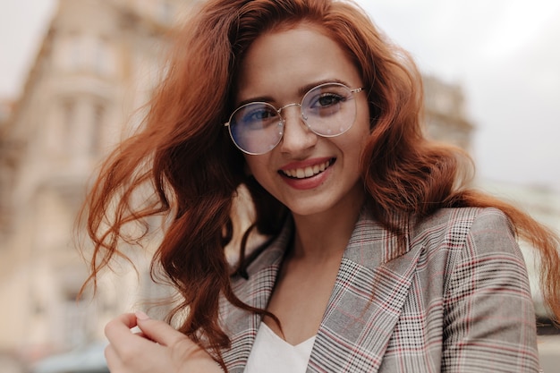 Pretty woman in eyeglasses and jacket looking into camera