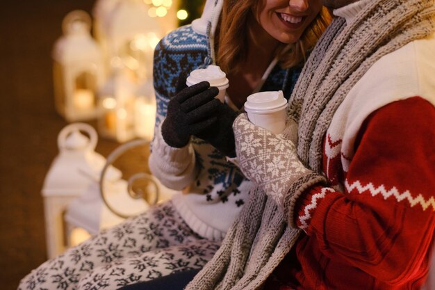 きれいな女性は、クリスマスイブに温かい飲み物を楽しんでいる男性に満足しています。
