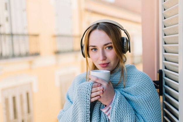 Pretty woman in headphones holding mug