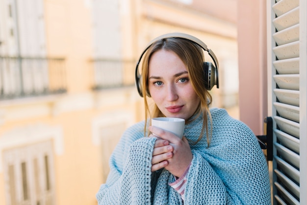 Pretty woman in headphones holding mug