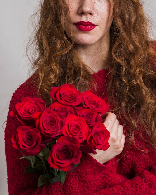 Free photo pretty woman holding a bouquet of roses