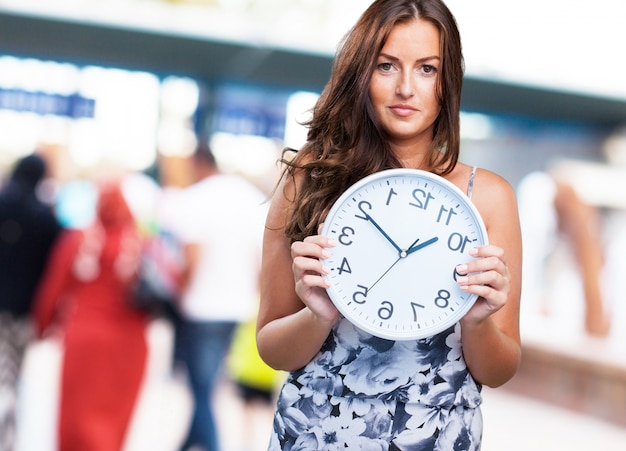 Free photo pretty woman holding a clock