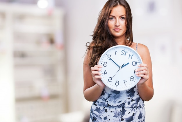 Free photo pretty woman holding a clock