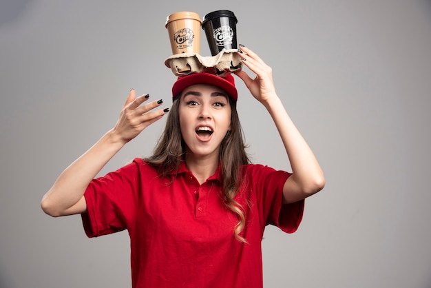 Free photo pretty woman holding coffee cups on her head.