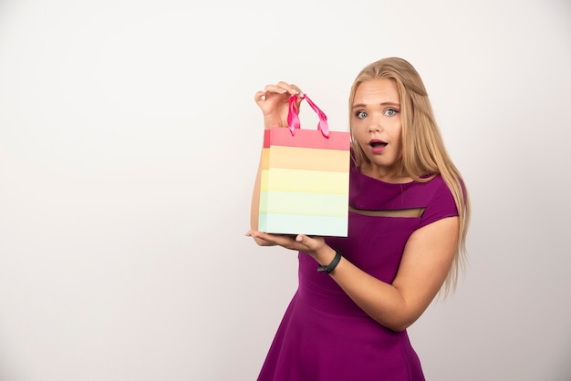 Pretty woman holding gift bag with happy expression. 