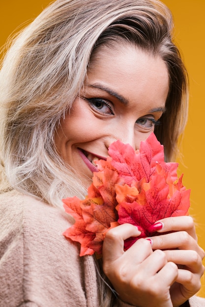 Free photo pretty woman holding maple leaves looking at camera