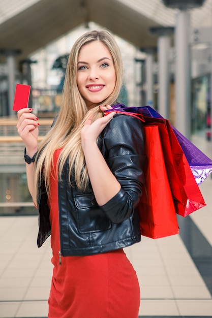 Free photo pretty woman holding shopping bags and showing blank credit card