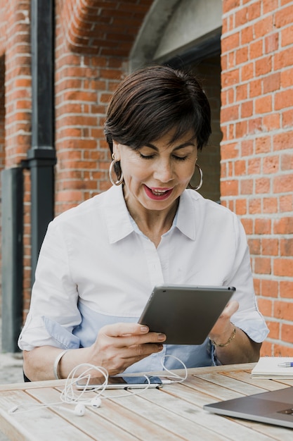 Free photo pretty woman holding a tablet outdoors