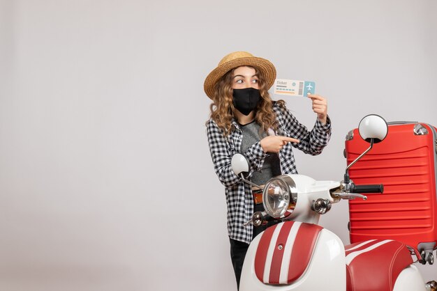 pretty woman holding ticket standing near moped grey