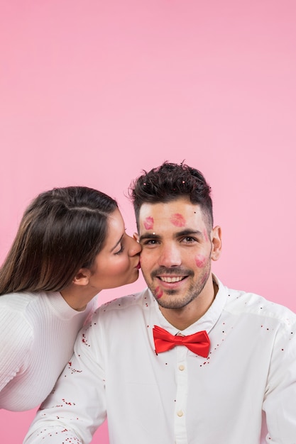 Pretty woman kissing man with lipstick kiss marks on cheek