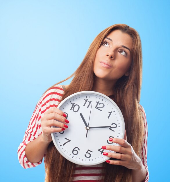 Pretty woman looking up holding a clock