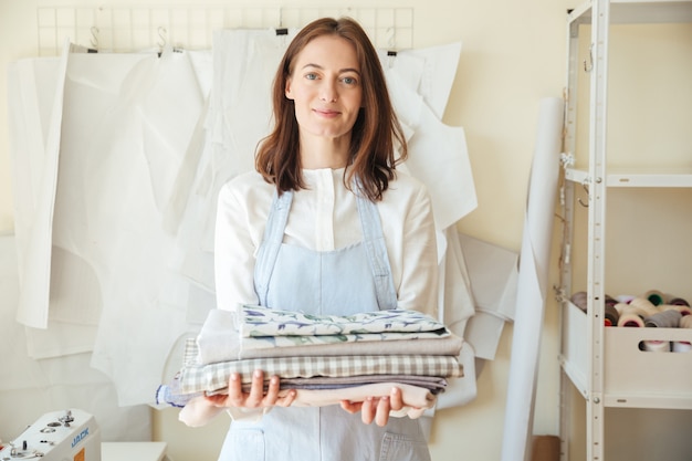 Pretty woman looking while holding pile of fabrics