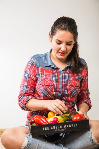 Pretty woman picking vegetables from pallet