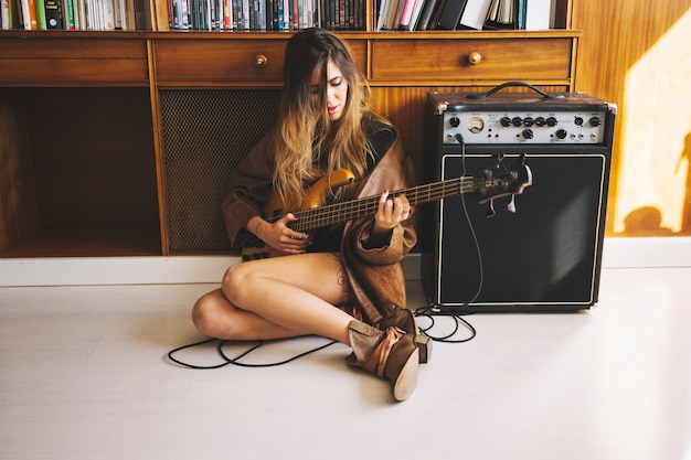Pretty woman playing guitar near cupboard