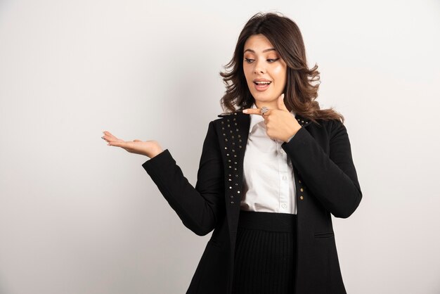 Pretty woman pointing at her hand on white.