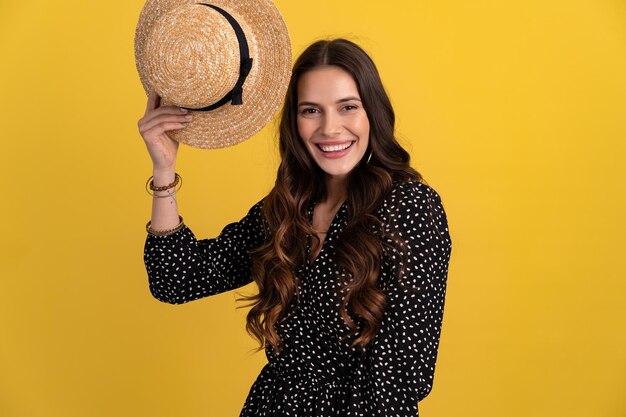 Foto gratuita bella donna in posa isolata su sfondo giallo con cappello di paglia e vestito