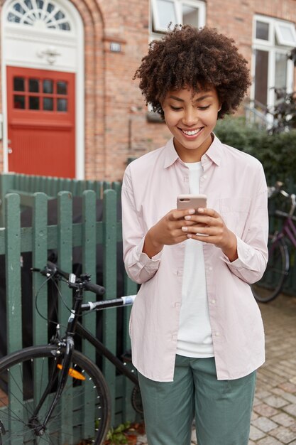 Foto gratuita bella donna in posa fuori con il suo telefono