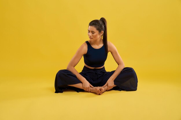 Pretty woman practicing butterfly II yoga pose in studio