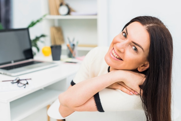 Foto gratuita donna graziosa che riposa sulla sedia in ufficio