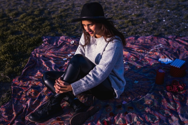 Free photo pretty woman sitting on coverlet on grass