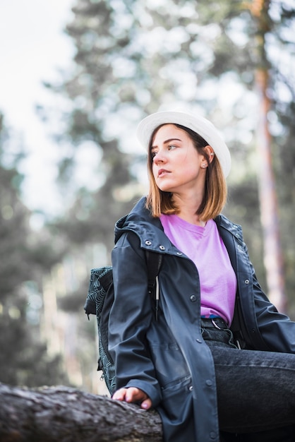 Free photo pretty woman sitting on log in forest