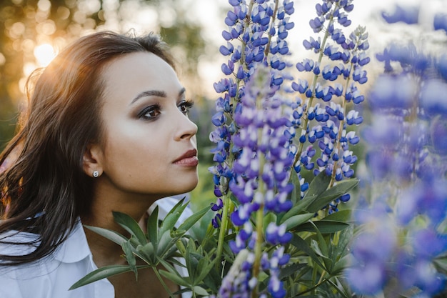 Pretty woman smells a bouquet of lupines