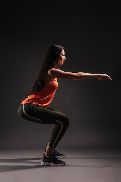 Pretty woman squatting on dark background