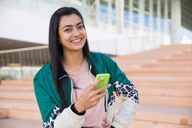 Pretty woman on stairs holding phone in hand, smiling