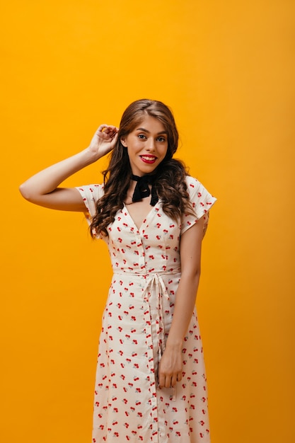 Pretty woman in stylish dress happily posing on orange background.Beautiful pretty girl in romantic clothes looking into camera.