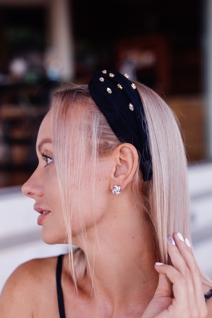 Free photo pretty woman in stylish headband wearing beautiful earrings