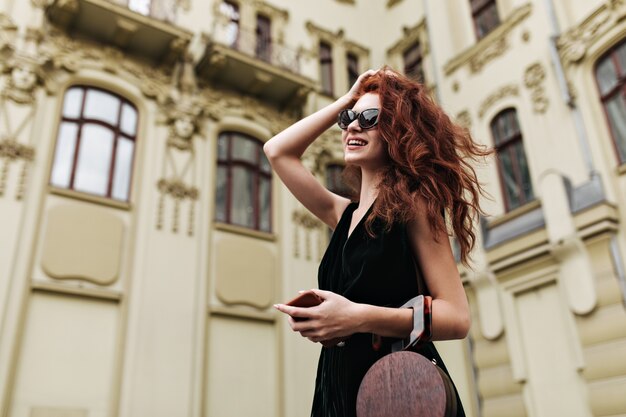 Pretty woman in sunglasses touching her hair and posing outside