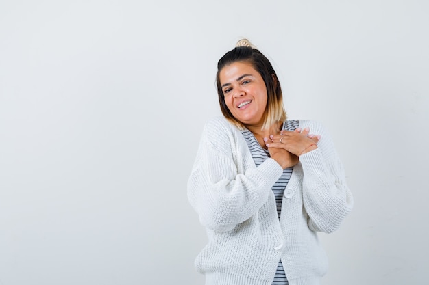 Foto gratuita bella donna in t-shirt, cardigan che si tiene per mano sul petto e sembra felice