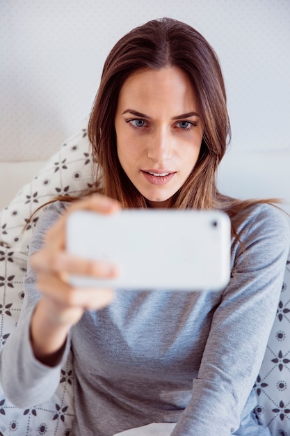 Free photo pretty woman taking selfie in bed