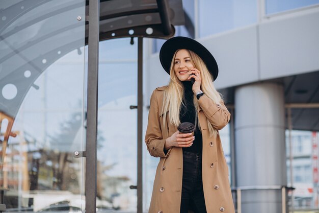 Pretty woman talking on the phone and waiting for bus