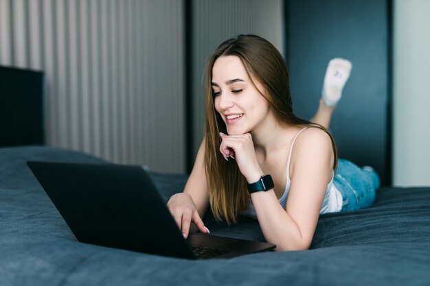 Pretty woman using her laptop in bed at home