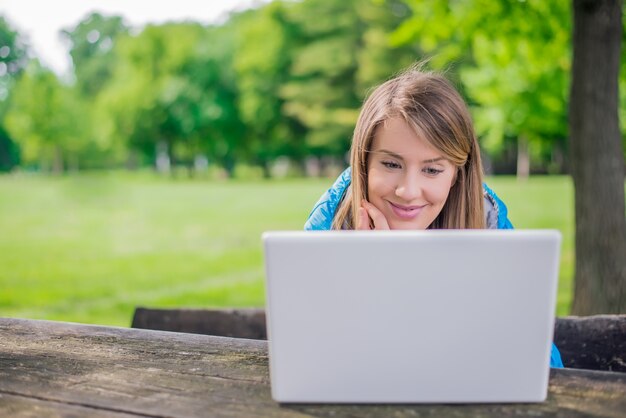 Красивая женщина, используя ноутбук в парке в солнечный день