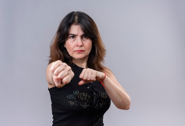 Foto gratuita bella donna che indossa una camicetta nera con rabbia facendo boxe e