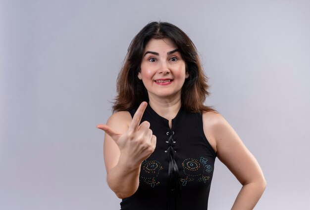 Pretty woman wearing black blouse doing happy forefinger up over gray background