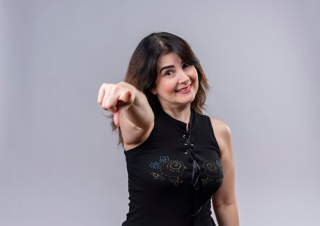 Pretty woman wearing black blouse  happily pointing on with forefinger