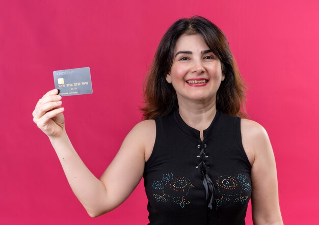 Pretty woman wearing black blouse looking  happily holding the card