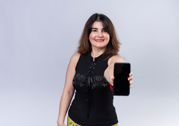 Pretty woman wearing black blouse looking  happily holding phone